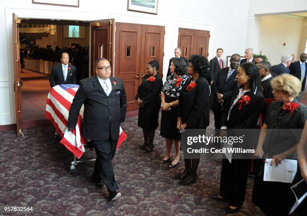 During Federal Judge Matthew J Perry's funeral at Brookland Baptist Church, mourners stand as Michael Perry wheels his father's flag-draped casket...