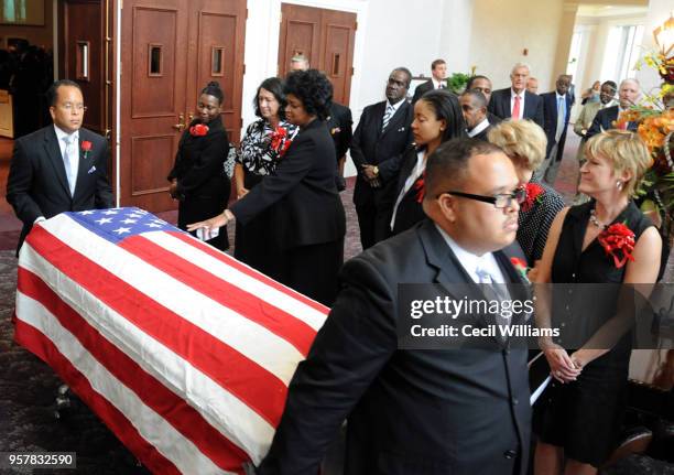 During Federal Judge Matthew J Perry's funeral at Brookland Baptist Church, mourners stand as Michael Perry wheels his father's flag-draped casket...