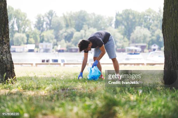 collecting trash in nature near riverbank - ivan jekic stock pictures, royalty-free photos & images