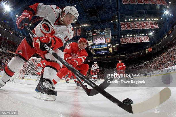 Brett Lebda of the Detroit Red Wings reaches over Zach Boychuk of the Carolina Hurricanes to dig the puck out of the boards during an NHL game at Joe...