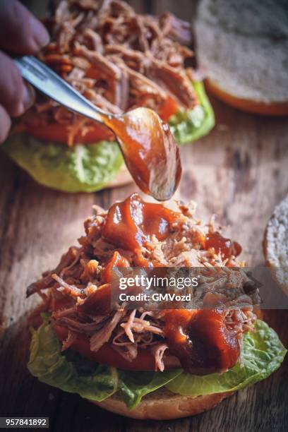 messy pulled pork burger with barbecue sauce and fresh salad - pulled pork stock pictures, royalty-free photos & images