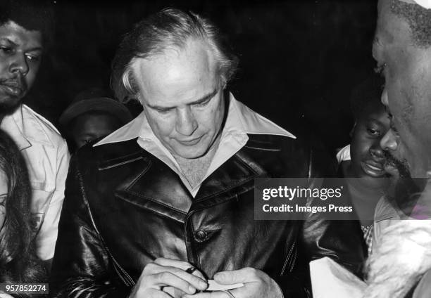 Marlon Brando signs autographs at the Apollo theater on March 11, 1974 in New York City.