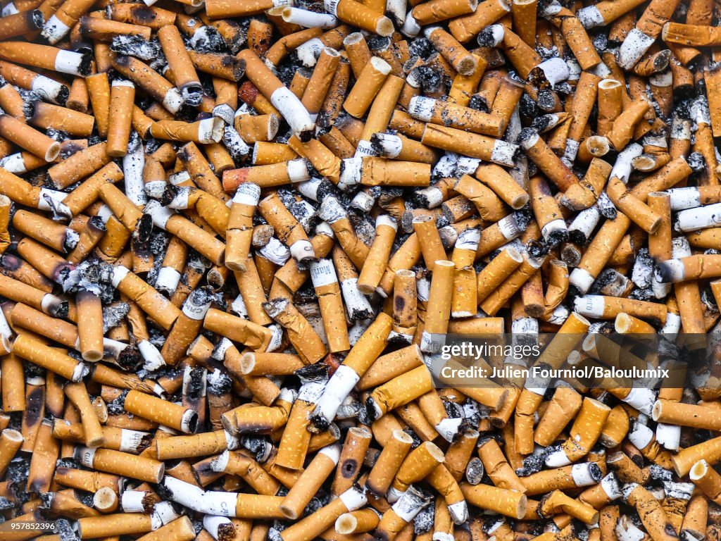 Cigarette butts in a public ashtray.