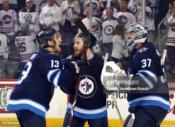 Brandon Tanev, Bryan Little and goaltender Connor Hellebuyck of the Winnipeg Jets celebrate a 4-2 victory over the Vegas Golden Knights in Game One...