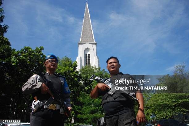 Police stand guard as Christian devotees attend a Sunday mass at the Saint Petrus church in Bandung on May 13, 2018. - A wave of blasts including a...