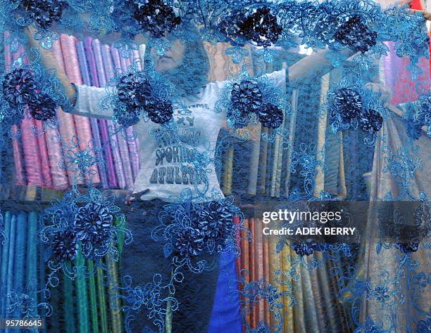 An Indonesian vendor holds textile fabrics at a shop in Jakarta on January 15, 2010. A new regional trade pact with China is on track, the ASEAN...