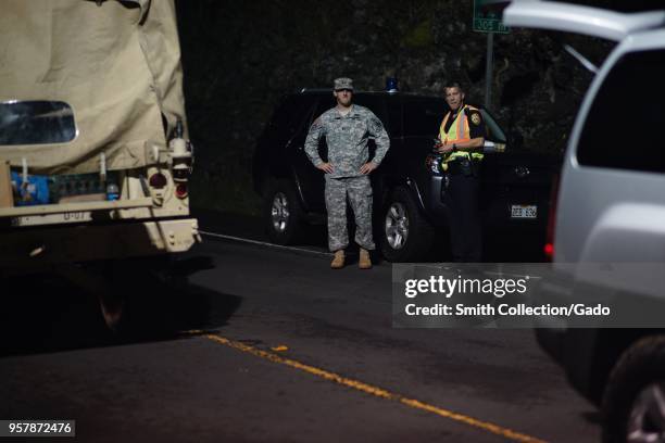 Hawaii Army National Guard Task Force Capt Brian Hunt speaking with a local police officer at a traffic control point during a volcanic outbreak,...