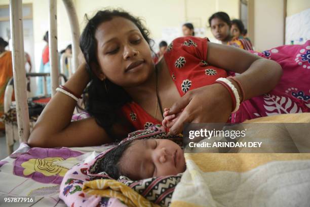 An Indian mother holds the hand of her new born infant at maternity ward of a government hospital during Mother's Day in Agartala, the capital of...