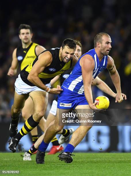 Ben Cunnington of the Kangaroos handballs whilst being tackled by Toby Nankervis of the Tigers during the round eight AFL match between the North...