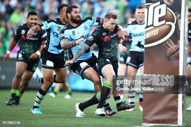 Blake Austin of the Raiders is tackled by Andrew Fifita of the Sharks as he scores a try during the round 10 NRL match between the Canberra Raiders...