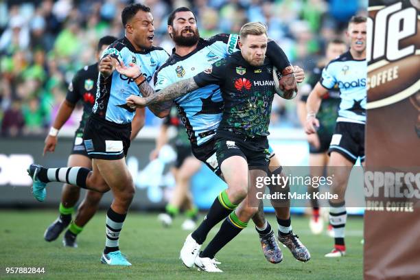 Blake Austin of the Raiders is tackled by Andrew Fifita of the Sharks as he scores a try during the round 10 NRL match between the Canberra Raiders...