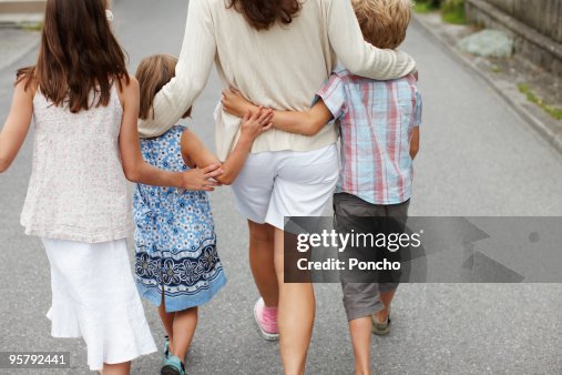 mother with three children walking and hugging