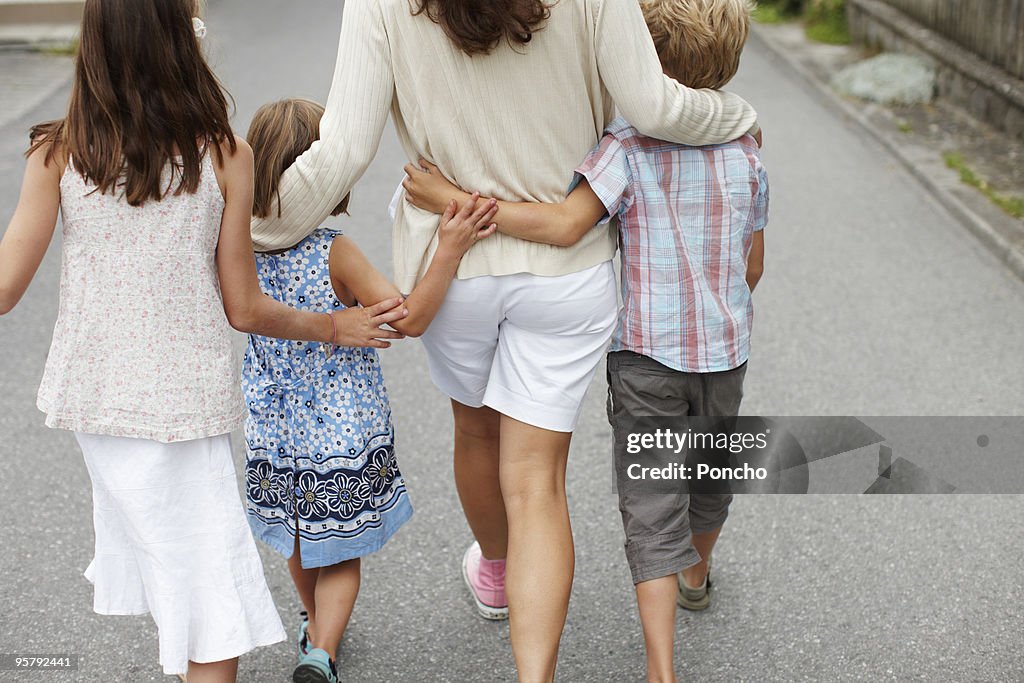 Mother with three children walking and hugging