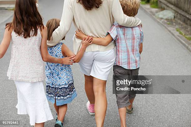 mother with three children walking and hugging - three children only stock pictures, royalty-free photos & images