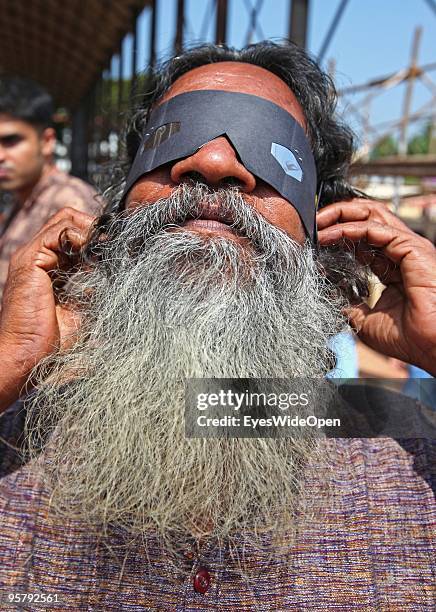 Indian man observes the rare Annular Solar Eclipse on January 15, 2010 at the central stadium of Thiruvananthapuram in Kerala, South India.This rare...