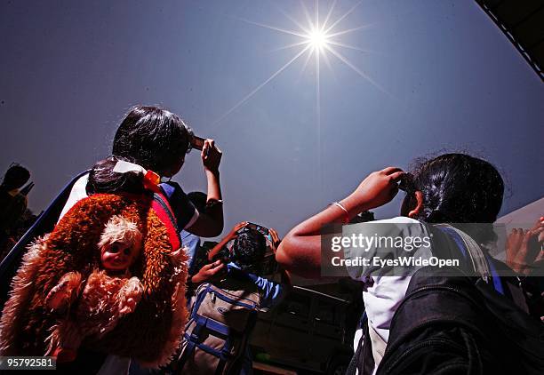 Indian people observe the rare Annular Solar Eclipse on January 15, 2010 at the central stadium of Thiruvananthapuram in Kerala, South India.This...