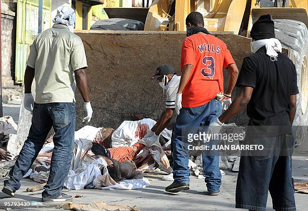 Group of men pile corpses in front of a bulldozer in Port-au-Prince on January 14 following the devastating earthquake that rocked Haiti on January...