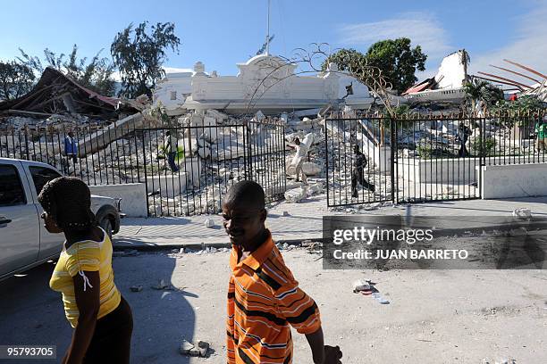 Locals walk in front of the collapsed Palace of Justice in Port-au-Prince, on January 14 following the devastating earthquake that rocked Haiti on...