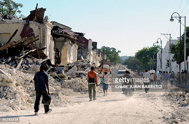 Locals walk in a destroyed street in Port-au-Prince, on January 14 following the devastating earthquake that rocked Haiti on January 12. Desperate...
