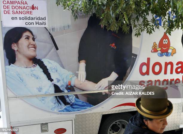 Bolivian Aymara woman walks by a truck displaying a poster promoting blood donation to help quake victims in Haiti, during a massive campaign...
