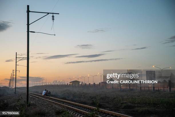 Men sit on the railway line near the airport in Kolwezi on May 7, 2018. - The airport was the site of the battles for Kolwezi, in May 1978 during the...