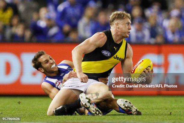 Josh Caddy of the Tigers is tackled by Jamie Macmillan of the Kangaroos during the 2018 AFL round eight match between the North Melbourne Kangaroos...