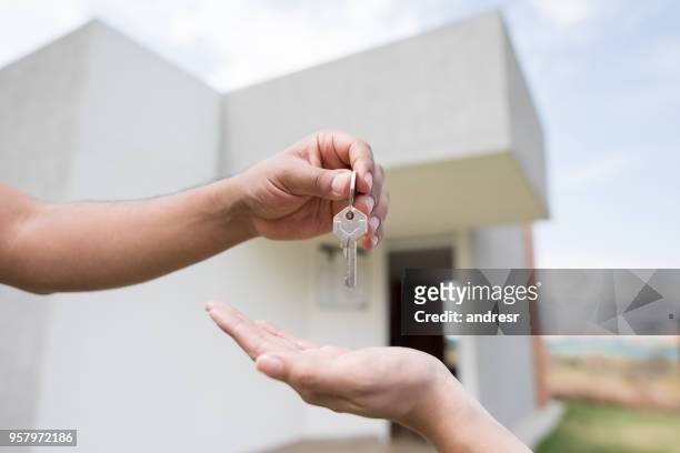 unrecognizable person giving the keys of a house to a new home owner - handing over keys stock pictures, royalty-free photos & images