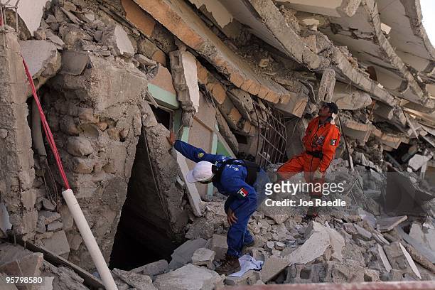 Search and Rescue workers from Mexico search for a way to reach survivors trapped under the rubble of what is left of the St Gerard building after...