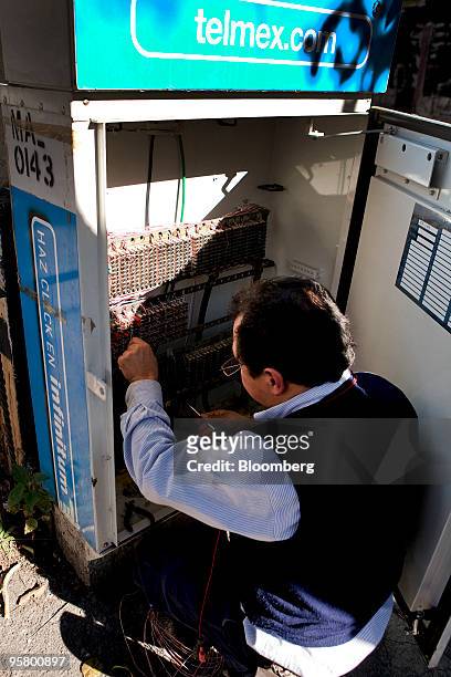 Telmex worker services a phone booth in Mexico City, Mexico, on Thursday, Jan. 14, 2010. Carlos Slim's America Movil SAB, the largest Latin American...