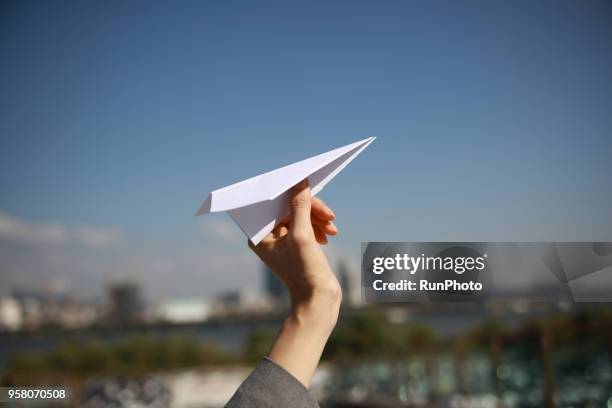 cropped hand of woman holding paper airplane against sky - launching in seoul stock pictures, royalty-free photos & images