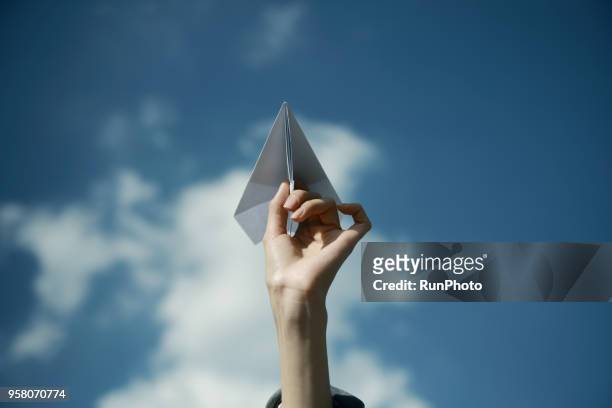 cropped hand of woman holding paper airplane against sky - paper blowing stock pictures, royalty-free photos & images