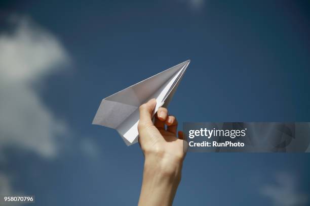 close up of woman holding paper plane toward sky - plane taking off stock-fotos und bilder