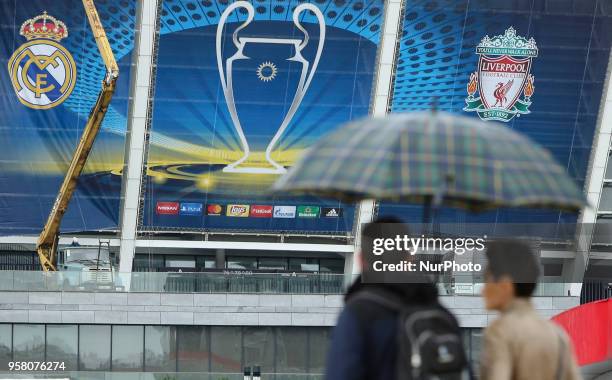 Couple under the umbrella walks past NSC Olimpiyskiy Stadium covered with banners for the Champions League in Kyiv, Ukraine, May 13, 2018. Kyiv...