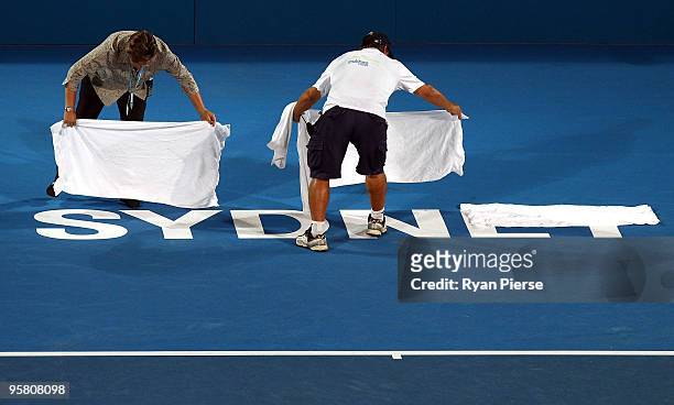 Court staff cover the court after rain stopped play during the men's final between Marcos Baghdatis of Cyrprus and Richard Gasquet of France during...