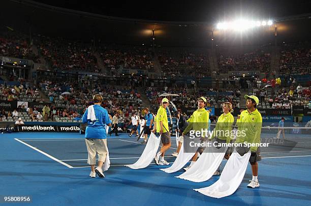 Ballboys wipe the court dry during a rain delay in the men's final between Marcos Baghdatis of Cyprus and Richard Gasquet of France during day seven...