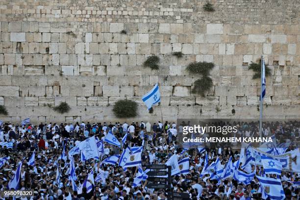 Isreali Israeli nationalist settlers wave their national flags at the Western Wall in Jerusalem's Old City on May 13 as they celebrate the Jerusalem...