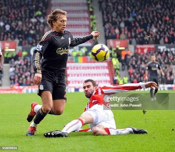 Danny Higginbotham of Stoke goes in on Lucas Levia of Liverpool during the Barclays Premier League match between Stoke City and Liverpool at...