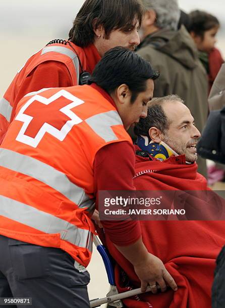 Red Cross member help a survivor of the huge earthquake that devastated Haiti on January 12, upon his arrival at the Torrejon de Ardoz airport in...