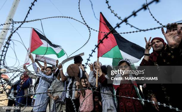 Girl raises a Palestinian flag as another Palestinian boy holds a wooden key symbolising the return, as they stand with others before the barbed-wire...