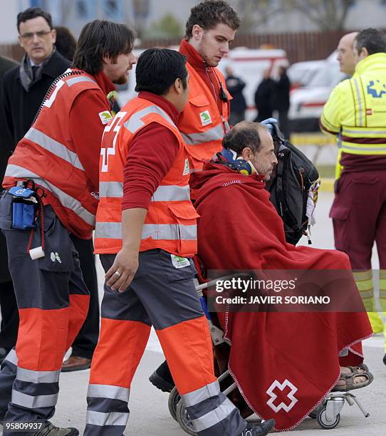 Red Cross members help a survivor of the huge earthquake that devastated Haiti on January 12, upon his arrival at the Torrejon de Ardoz airport in...