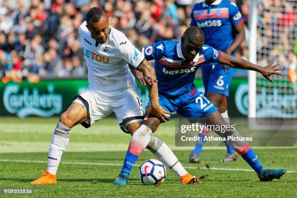 Jordan Ayew of Swansea City challenged by Badou Ndiaye of Stoke City during the Premier League match between Swansea City and Stoke City at The...