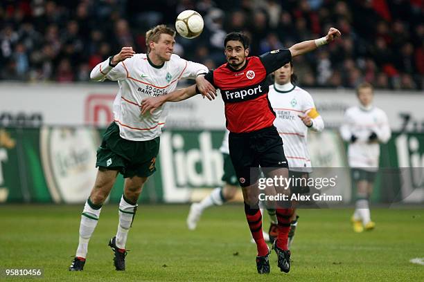 Per Mertesacker of Bremen is challenged by Nikos Liberopoulos of Frankfurt during the Bundesliga match between Eintracht Frankfurt and Werder Bremen...