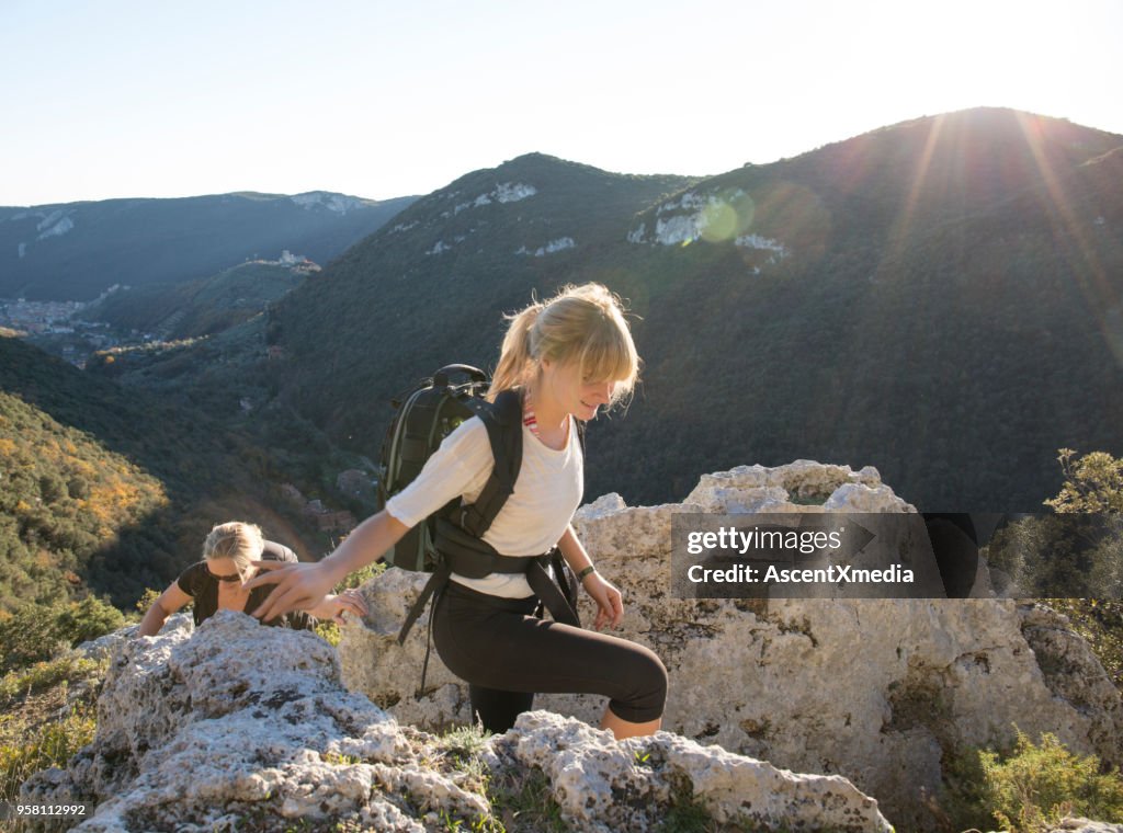Mother and daughter hiking in mountains in sunlight