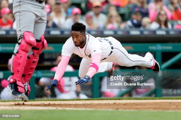 Niko Goodrum of the Detroit Tigers dives into home plate to score against the Seattle Mariners from second base on a single by Mikie Mahtook during...