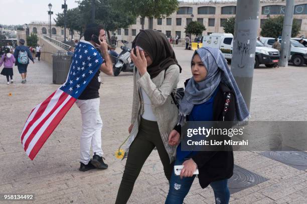 Palestinian women walks next to a man wearing an American flag outside the Old City on May 13, 2018 in Jerusalem, Israel. Israel mark Jerusalem Day...