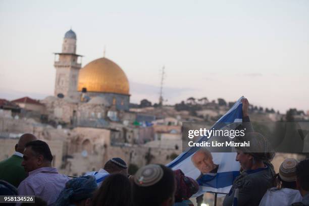 Israelis hold an Israeli flag with an image of Israeli Prime Minister Benjamin Netanyahu next to the Western Wall on May 13, 2018 in Jerusalem,...