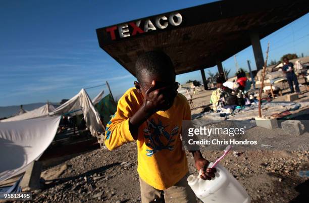 Haitian child washes his face at a makeshift camp at a fuel station January 16, 2010 on the edge of Port-au-Prince, Haiti. Haiti is trying to recover...