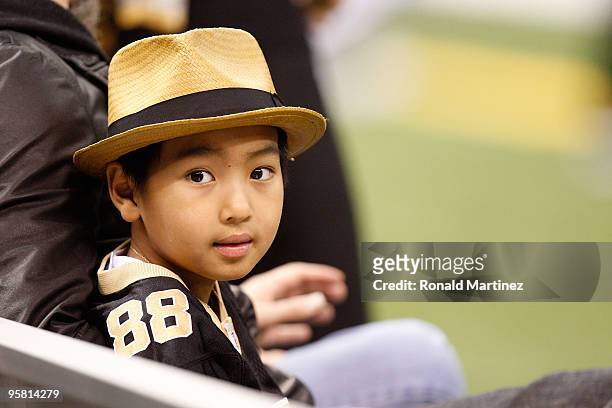 Maddox Jolie-Pitt sits on the bench on the sidelines during warm ups prior to the New Orleans Saints hosting the Arizona Cardinals during the NFC...