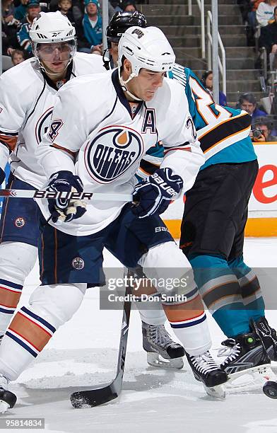 Denis Grebeshkov and Steve Staios of the Edmonton Oilers battle with Manny Malhotra of the San Jose Sharks during an NHL game on January 16, 2010 at...