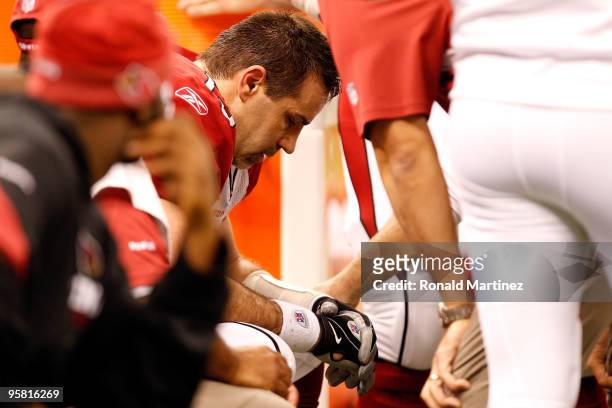 Quarterback Kurt Warner of the Arizona Cardinals sits on the bench with his head down as he is tended to by the medical staff after he took a hard...